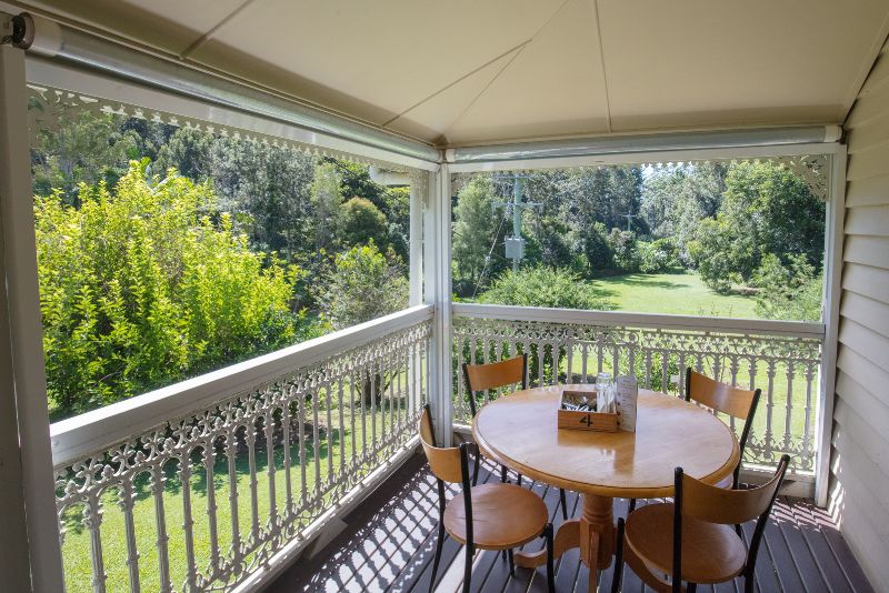 a verandah with a round dining table and four chairs and railing all round